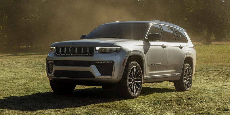 2025 Jeep Grand Cherokee SUV parked on a grassy field.