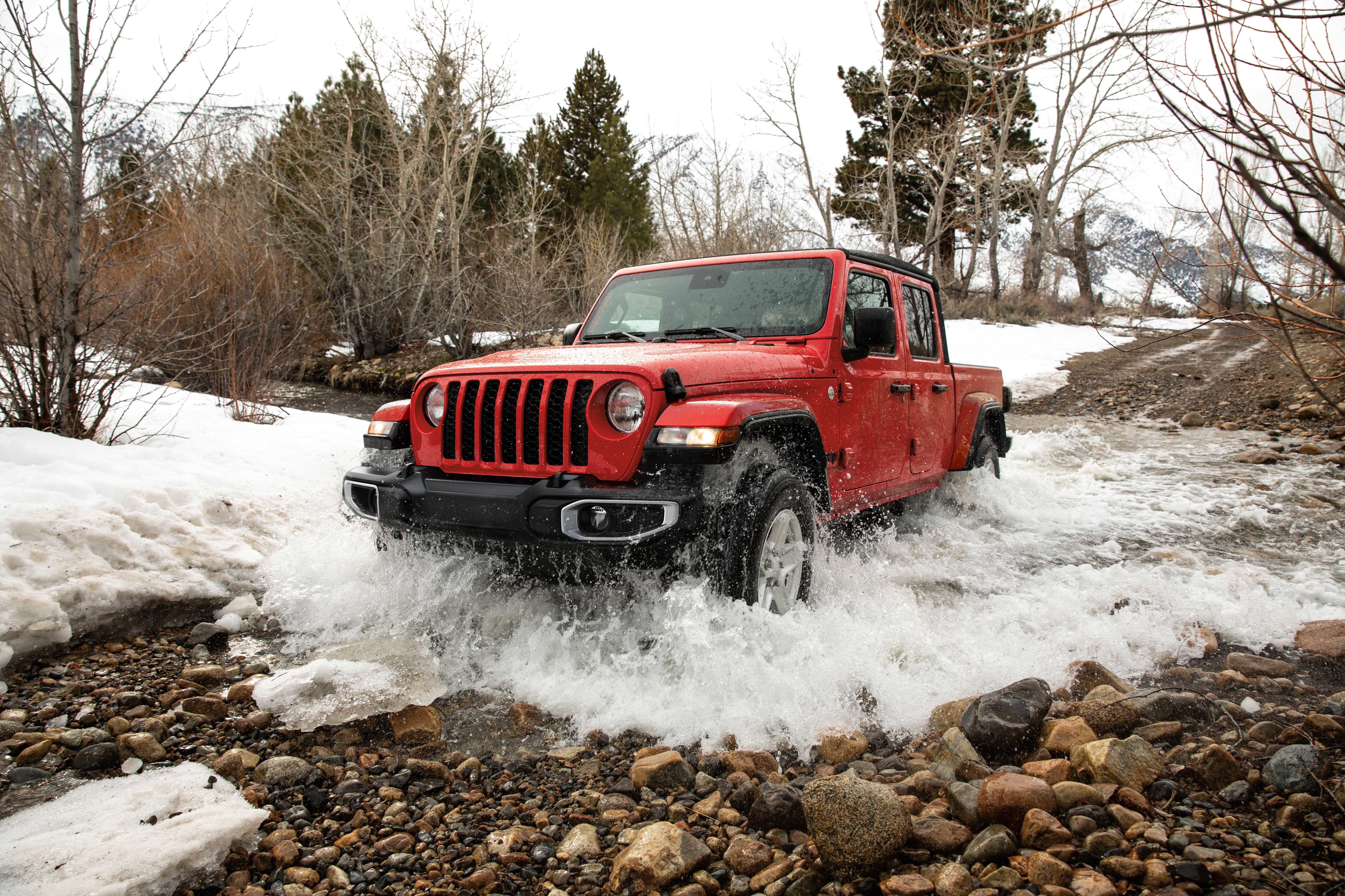 Jeep Gladiator pickup truck driving through snowy water terrain.